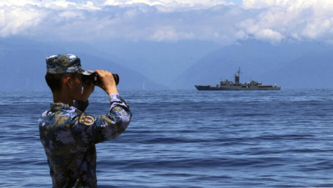 In this photo provided by Chinas Xinhua News Agency, a People's Liberation Army member looks through binoculars during military exercises as Taiwans frigate Lan Yang is seen at the rear, on Friday, Aug. 5, 2022. China is holding drills in waters around Taiwan in response to a recent visit by U.S. House Speaker Nancy Pelosi. (Lin Jian/Xinhua via AP)
