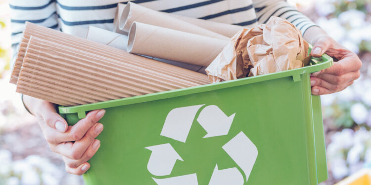 Eco-friendly person taking care of ecosystem by sorting paper to green container. Recycling concept
