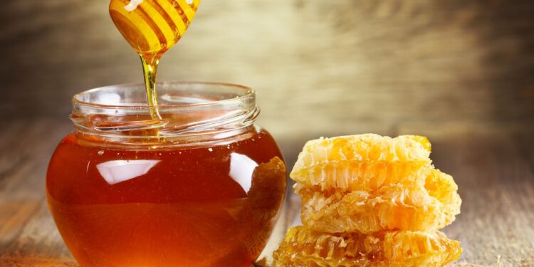 jar of honey with honeycomb on wooden table