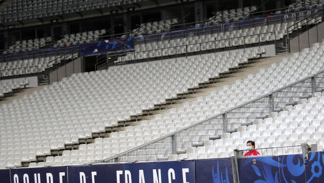 A steward wearing a face mask sits in near empty stands during the French Cup soccer final match between Paris Saint Germain and Saint Etienne at Stade de France stadium, in Saint Denis, north of Paris, Friday July 24, 2020. (AP Photo/Francois Mori)
