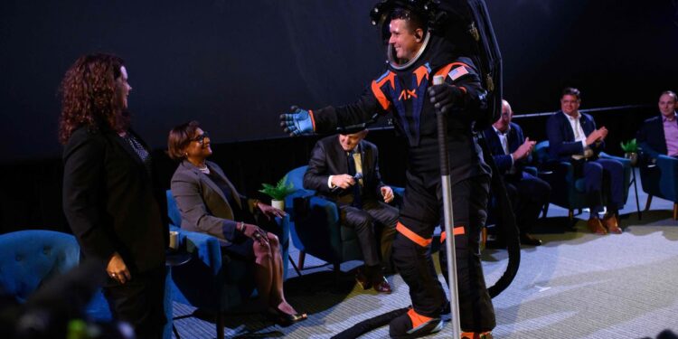 Chief Engineer Jim Stein goes to hug to NASAs Lara Kearney while wearing the new spacesuit during the Axiom Space Artemis III Lunar Spacesuit event at Space Center Houston in Houston, Texas, on March 15, 2023. - "Since a spacesuit worn on the Moon must be white to reflect heat and protect astronauts from extreme high temperatures, a cover layer is currently being used for display purposes only to conceal the suits proprietary design, " Axion said in a press release. (Photo by Mark Felix / AFP)