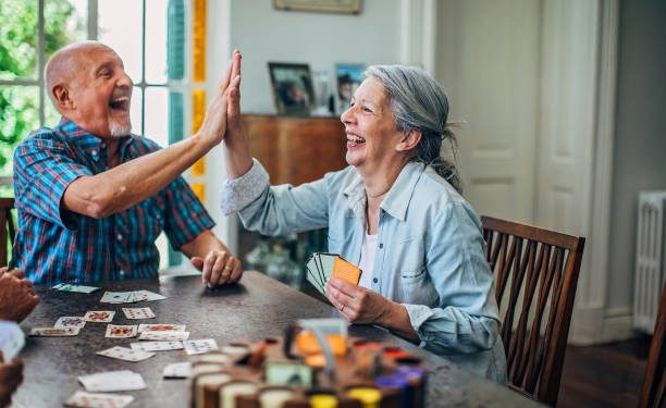 Man and woman, senior couple playing cards in nursing home.
