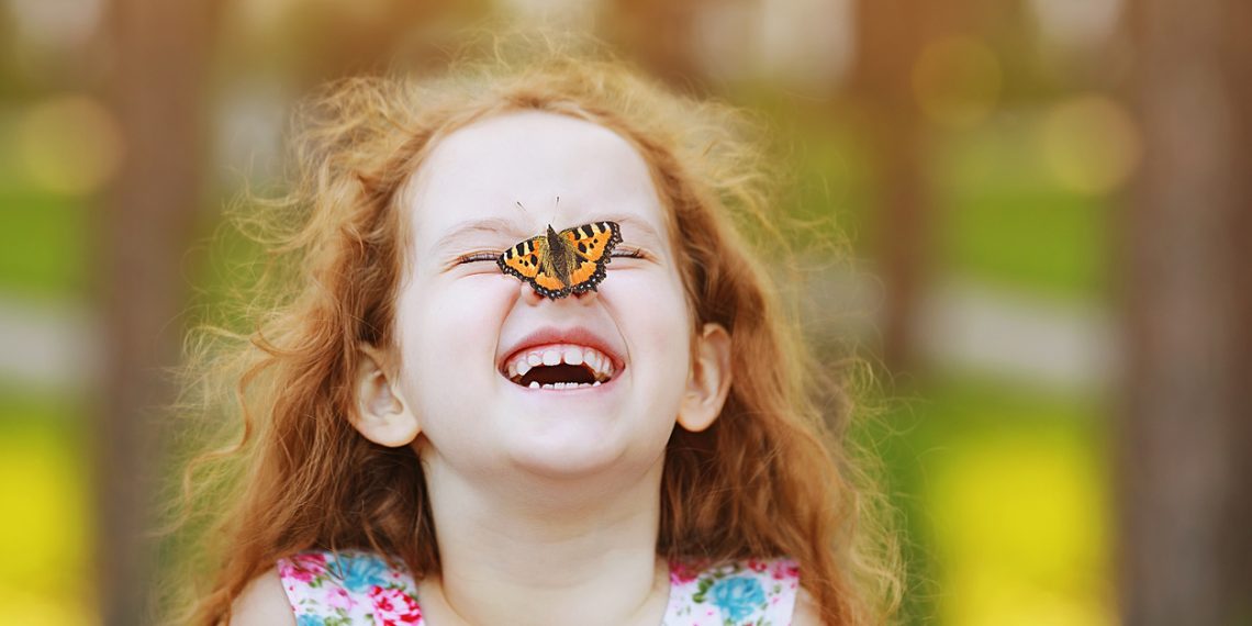 Funny laughing curly girl with a butterfly on his nose. Healthy smile with white teeth. Free breathing concept.