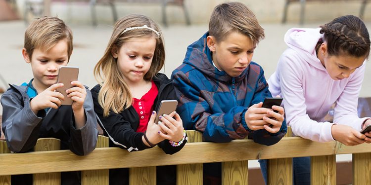 Les réseaux sociaux, un danger sur la santé psychologique et mentale des enfants 1 - Le Progrès Egyptien Outdoor portrait of  positive european girls and boys playing with phones