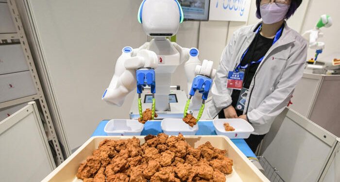 Japon : L’IA pour pallier le manque de main-d’œuvre 1 - Le Progrès Egyptien A robot sorts and places pieces of fried chicken into containers, during a demonstration by Japanese robotics company RT Corporation, on the first day of the 2023 International Robot Exhibition at the Tokyo International Exhibition Center in Tokyo on November 29, 2023. (Photo by Richard A. Brooks / AFP)