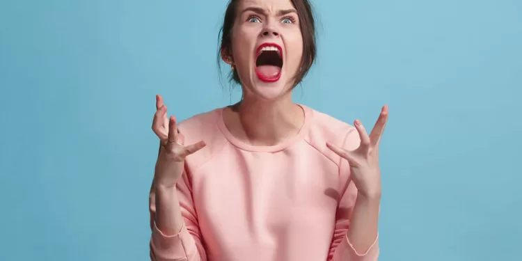 Screaming, hate, rage. Crying emotional angry woman screaming on blue studio background. Emotional, young face. Female half-length portrait. Human emotions, facial expression concept. Trendy colors