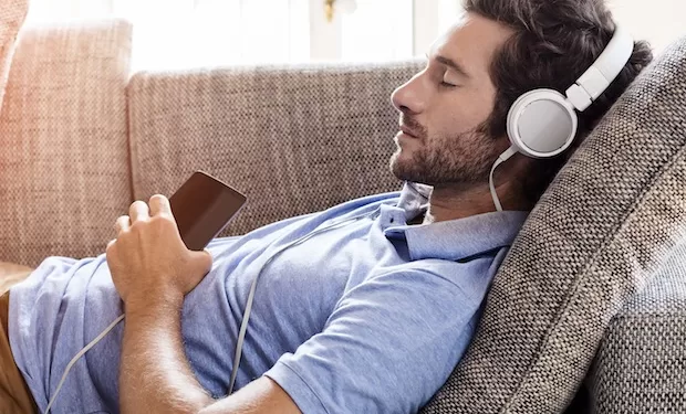 Young male couch listen headphones  mobile phone  at home