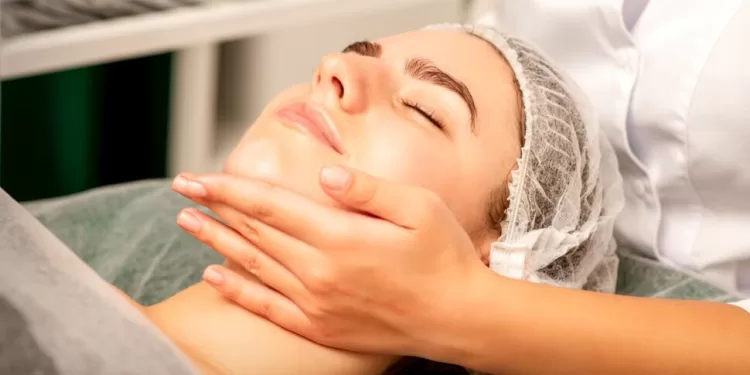 Facial massage. Hands of a masseur massaging neck of a young caucasian woman in a spa salon, the concept of health massage