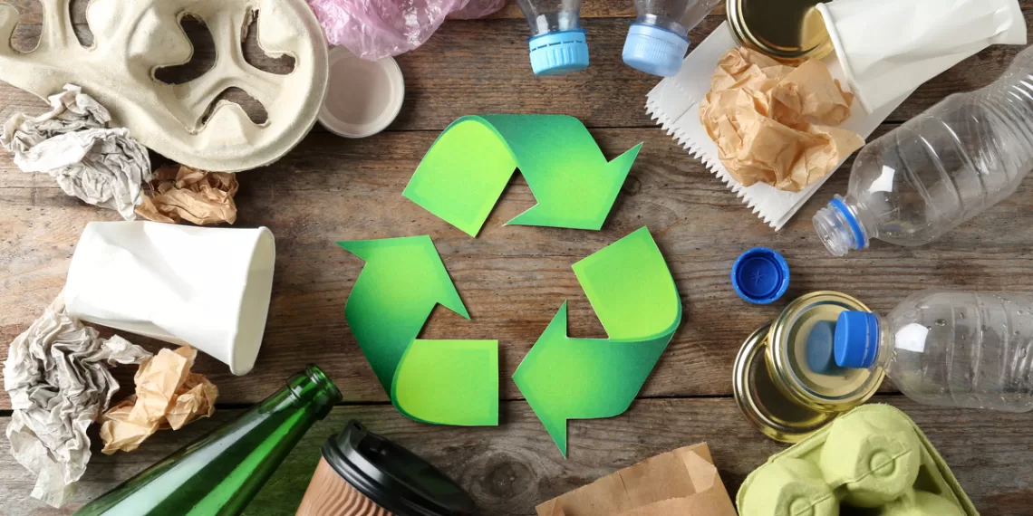 Recycling symbol and different garbage on wooden background, top view